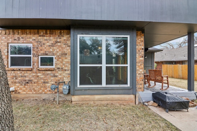 view of side of home featuring fence and brick siding