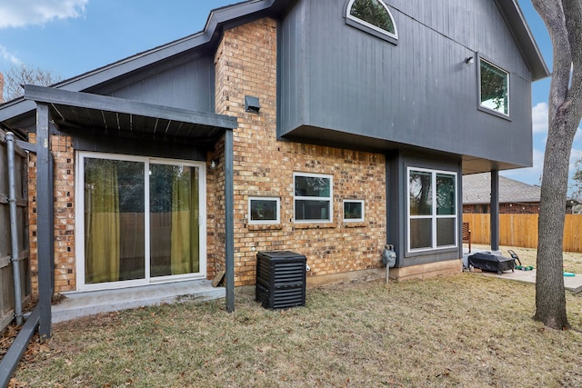 back of house featuring brick siding, fence, and a lawn