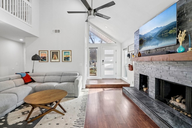 living room with visible vents, ceiling fan, wood finished floors, a fireplace, and high vaulted ceiling