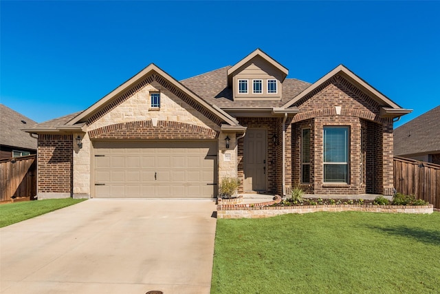 view of front facade with brick siding, fence, a front yard, a garage, and driveway