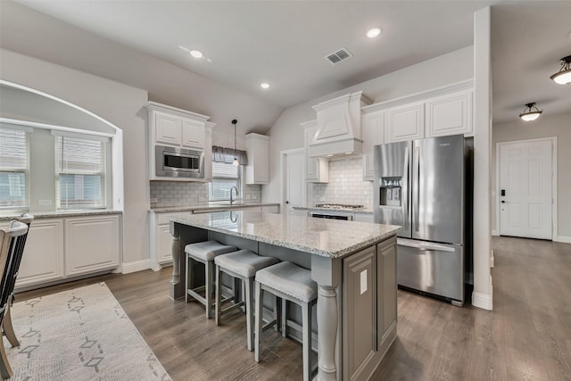 kitchen with visible vents, a sink, white cabinetry, stainless steel appliances, and custom exhaust hood