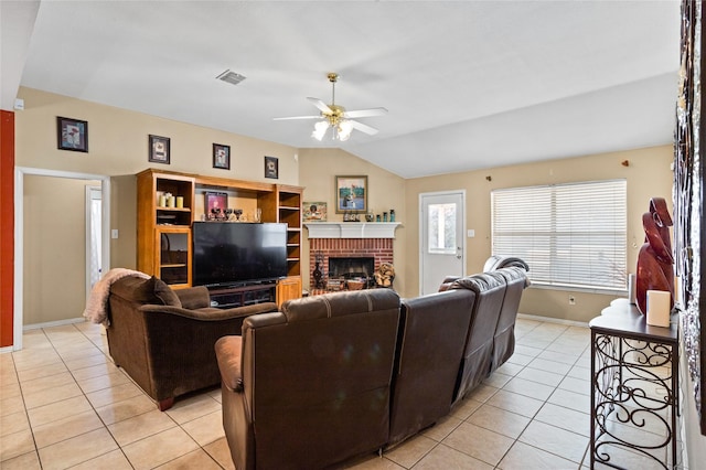 living area with visible vents, lofted ceiling, a brick fireplace, and light tile patterned flooring