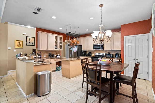 kitchen with light stone countertops, visible vents, a peninsula, a sink, and appliances with stainless steel finishes