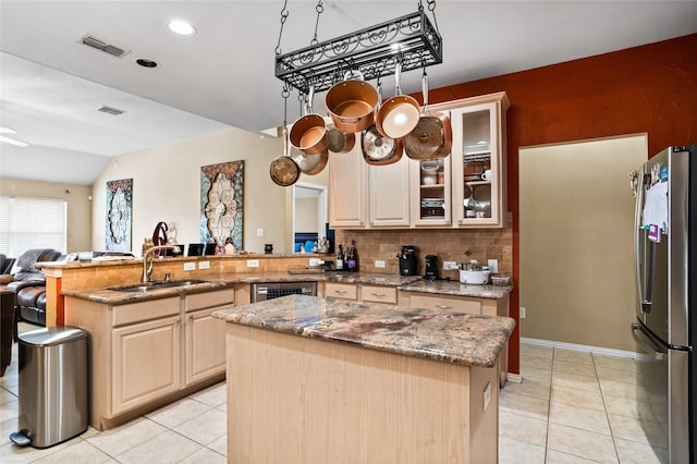 kitchen featuring tasteful backsplash, visible vents, a peninsula, freestanding refrigerator, and a sink