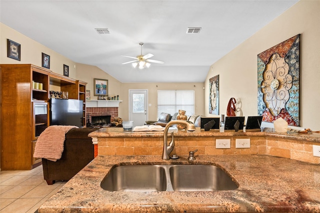 kitchen with visible vents, open floor plan, light stone counters, light tile patterned floors, and a sink