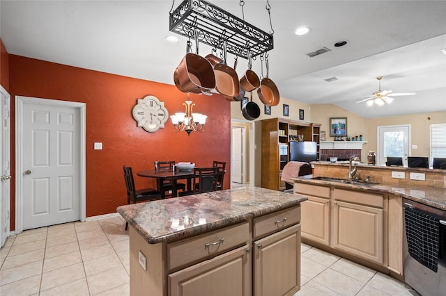 kitchen with visible vents, a kitchen island, a fireplace, light tile patterned flooring, and a sink