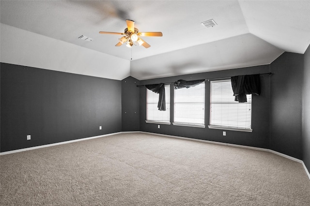 spare room with visible vents, carpet floors, baseboards, and vaulted ceiling