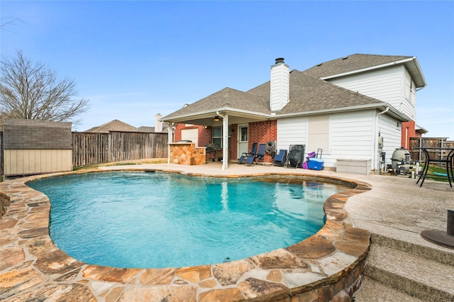 view of swimming pool featuring a fenced in pool, a fenced backyard, an outdoor structure, a storage unit, and a patio area