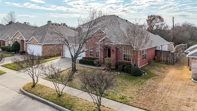 view of front of home with fence, an attached garage, a shingled roof, concrete driveway, and brick siding