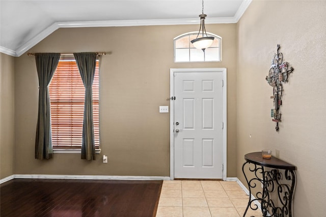 tiled foyer featuring crown molding, baseboards, and vaulted ceiling