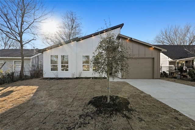 exterior space with driveway, board and batten siding, an attached garage, and fence