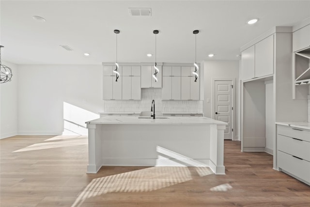 kitchen featuring visible vents, decorative backsplash, modern cabinets, white cabinetry, and a sink