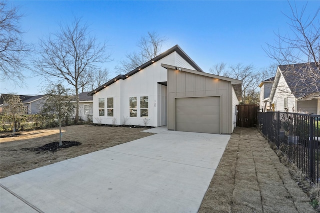 view of front facade with concrete driveway, an attached garage, and fence