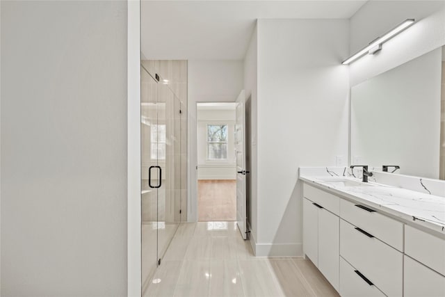 bathroom featuring baseboards, a shower stall, and vanity