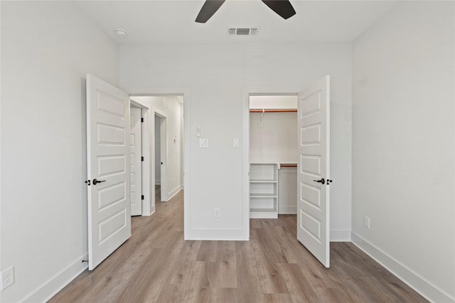 unfurnished bedroom with a closet, visible vents, light wood-style flooring, a spacious closet, and baseboards