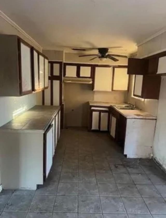 kitchen featuring ceiling fan, dark tile patterned flooring, a sink, and white cabinetry