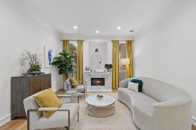 living area featuring ornamental molding, a premium fireplace, wood finished floors, and baseboards