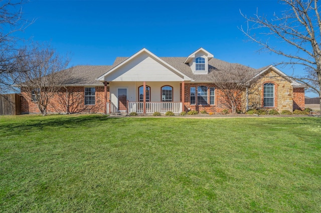 view of front of house featuring a shingled roof, fence, a front lawn, a porch, and brick siding