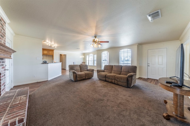 living room featuring baseboards, visible vents, ceiling fan, a textured ceiling, and crown molding