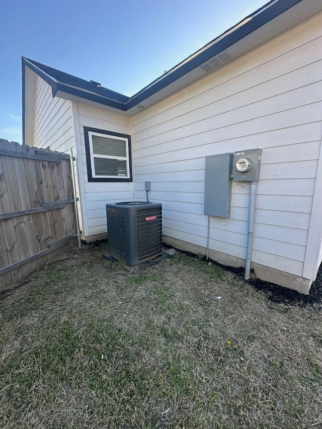 view of side of home featuring central AC unit and fence