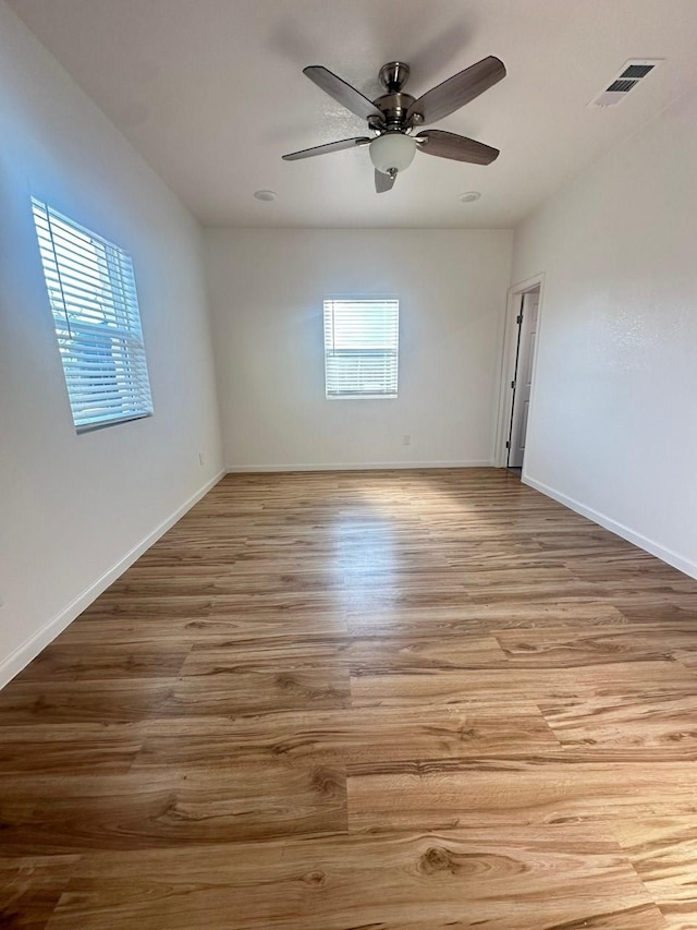 spare room featuring visible vents, wood finished floors, a wealth of natural light, and baseboards