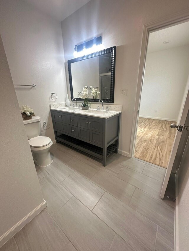 full bathroom featuring double vanity, an enclosed shower, a sink, and toilet