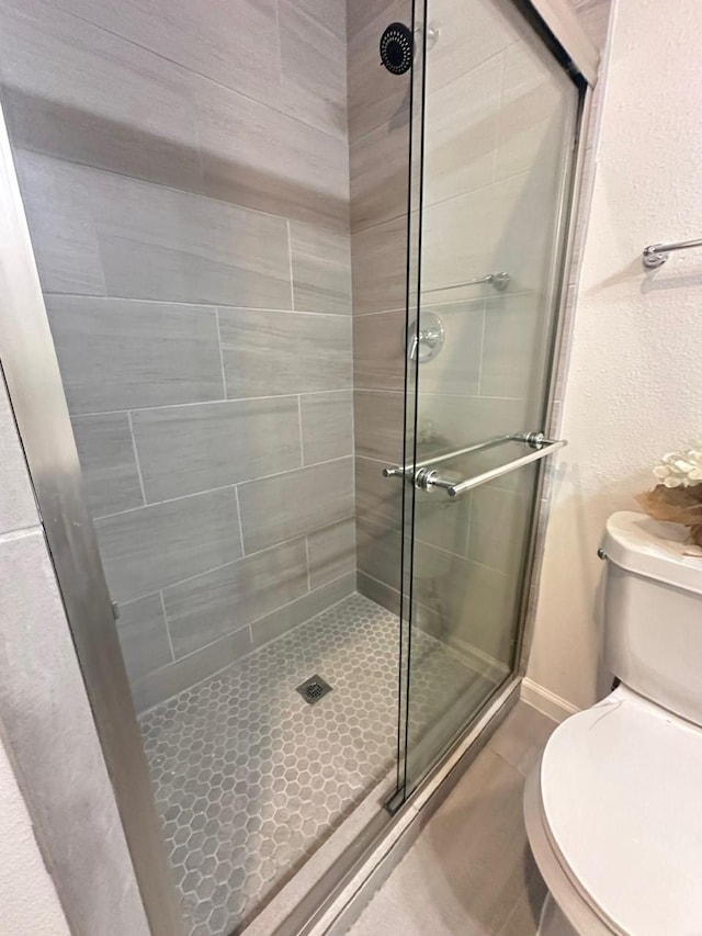 full bath featuring baseboards, a shower stall, and toilet