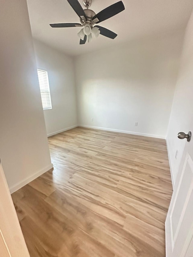 spare room featuring light wood-style flooring, baseboards, and a ceiling fan