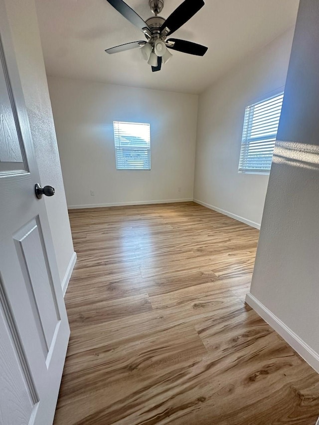 empty room with light wood-style floors, baseboards, and a ceiling fan