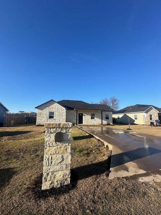 view of front of property with a front yard, stone siding, and fence