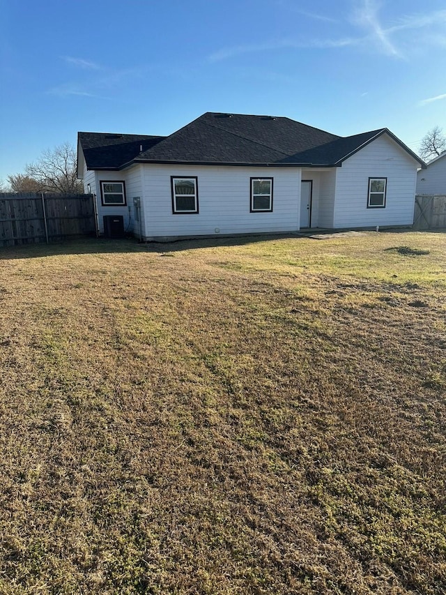 back of property with a lawn, central AC unit, and fence