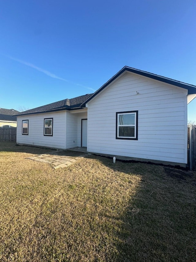 rear view of house with fence and a yard