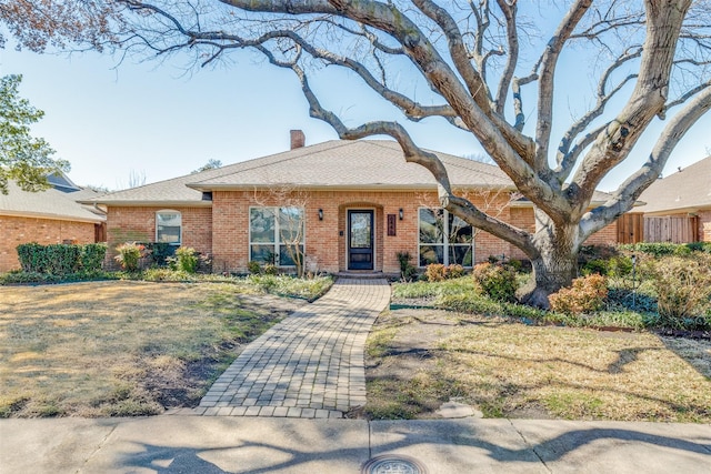 view of front of property with a front yard, a chimney, fence, and brick siding