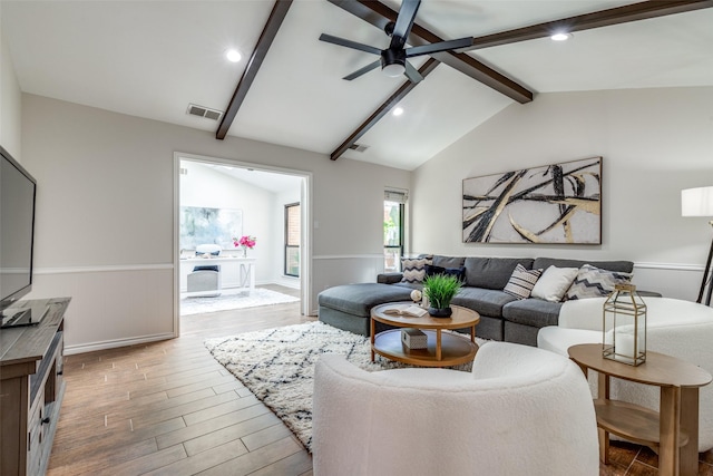 living room with visible vents, ceiling fan, lofted ceiling with beams, and wood finished floors