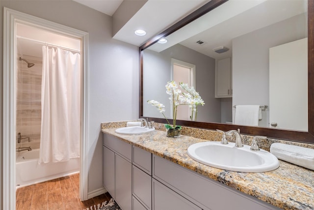 bathroom featuring shower / tub combo with curtain, visible vents, a sink, and wood finished floors