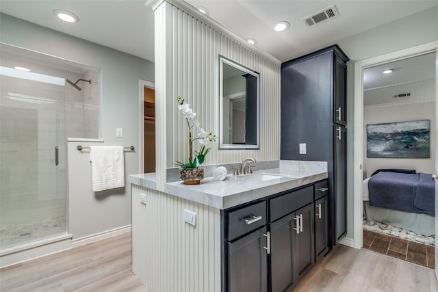 ensuite bathroom with a stall shower, wood finished floors, and visible vents