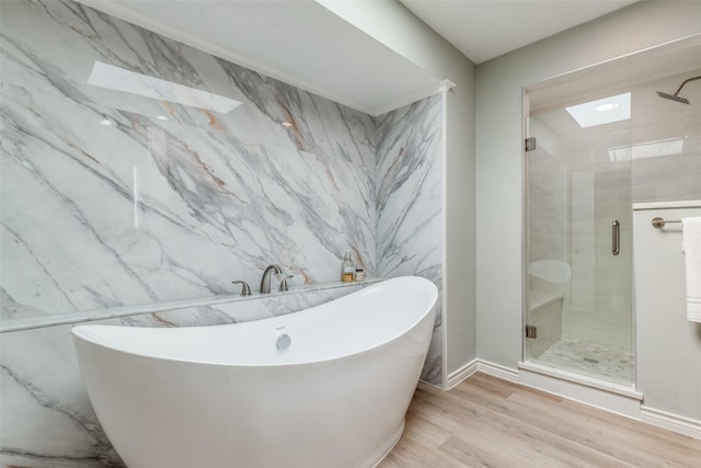 bathroom with wood finished floors, a freestanding tub, and a shower stall