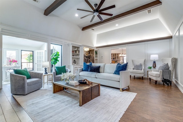 living room with a high ceiling, wood finished floors, beam ceiling, and a decorative wall