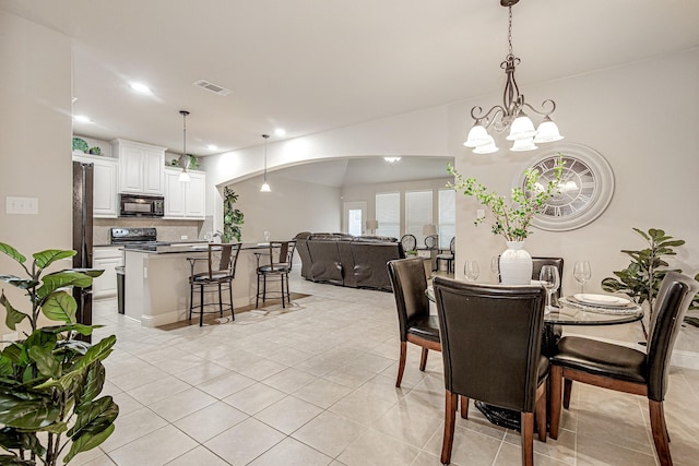 dining area with arched walkways, light tile patterned floors, recessed lighting, visible vents, and a chandelier