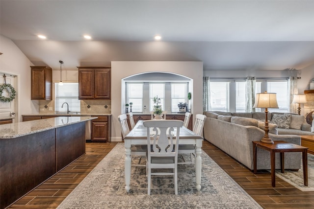 kitchen featuring vaulted ceiling, open floor plan, decorative backsplash, and wood finish floors