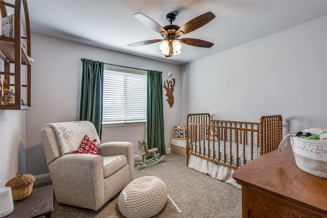 carpeted bedroom with a nursery area, baseboards, and a ceiling fan