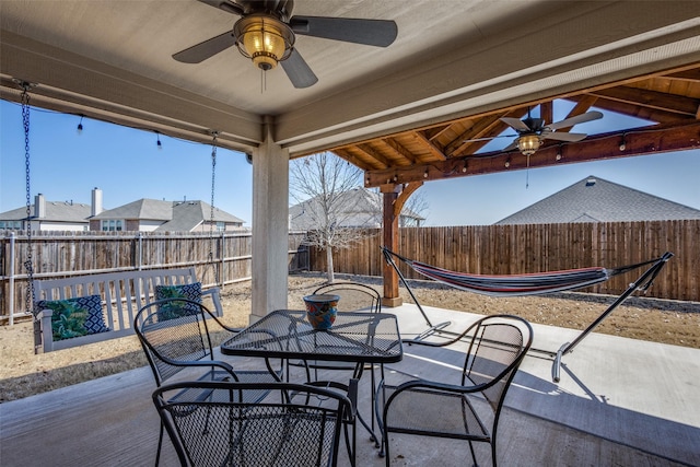 view of patio with outdoor dining space, a fenced backyard, ceiling fan, and a gazebo