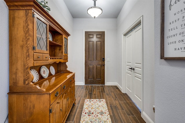 doorway featuring baseboards and wood finish floors