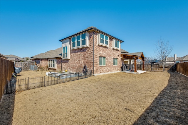 back of house with a lawn, a patio, a fenced backyard, central AC, and brick siding