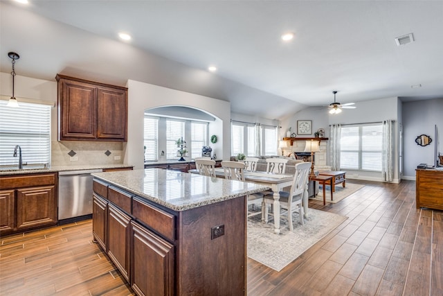 kitchen with light wood-style flooring, open floor plan, stainless steel dishwasher, a fireplace, and a sink