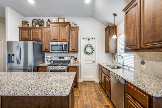 kitchen featuring tasteful backsplash, lofted ceiling, dark wood-style floors, appliances with stainless steel finishes, and a sink