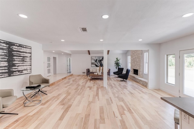 sitting room with light wood-style floors, recessed lighting, visible vents, and a stone fireplace