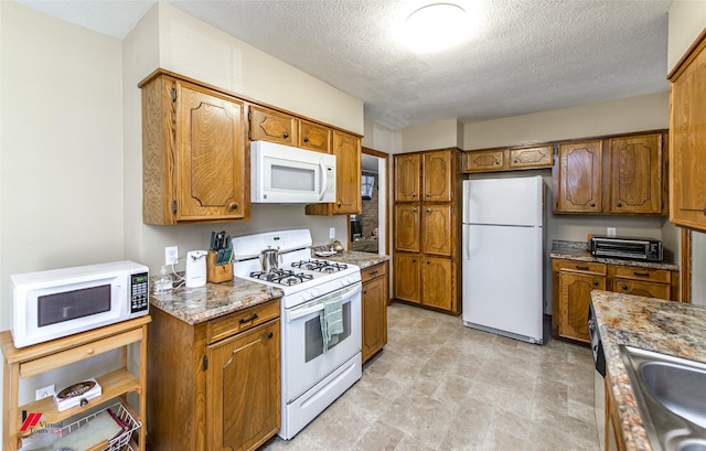 kitchen featuring white appliances, a toaster, brown cabinetry, and a sink