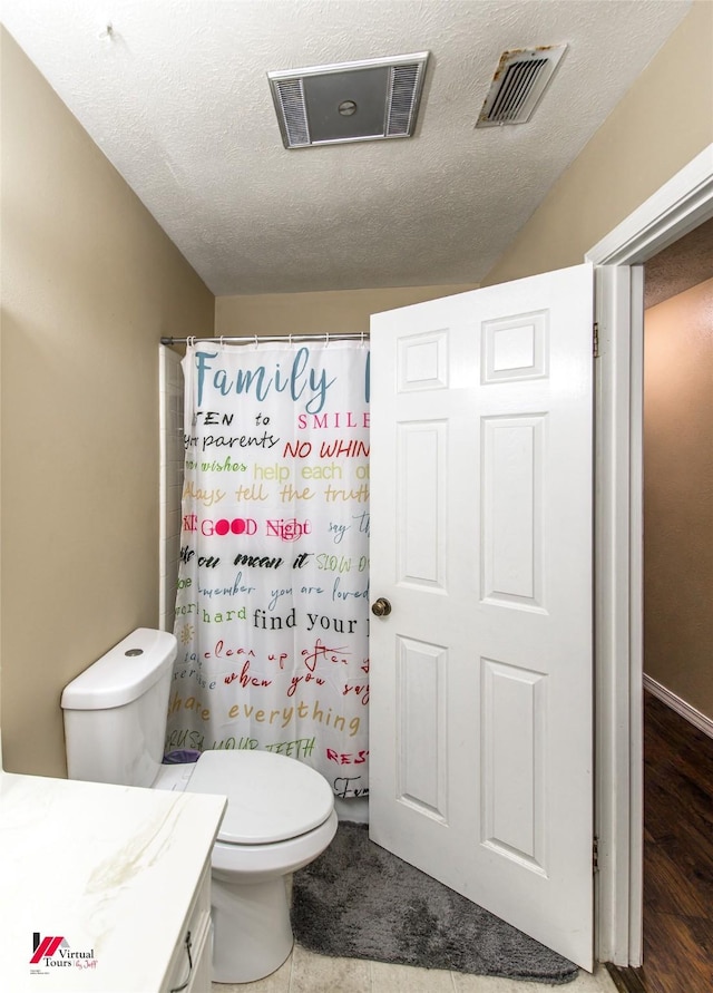 bathroom featuring visible vents, vanity, toilet, and a textured ceiling