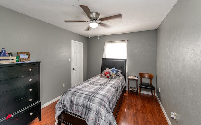 bedroom featuring a textured wall, ceiling fan, baseboards, and wood finished floors